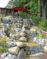 A 12,000 gallon per hour waterfall disappears into a pool of washed river stone at the base of the slope.